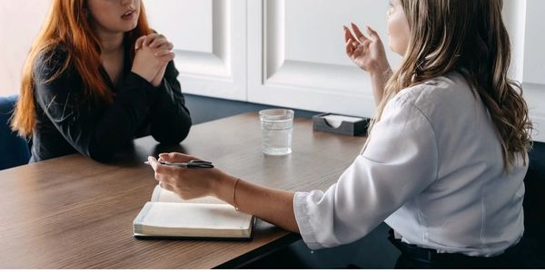Two women having a conversation at a table.