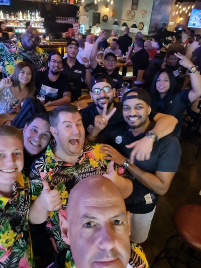 Group of friends having fun and posing for a lively selfie at a busy bar.