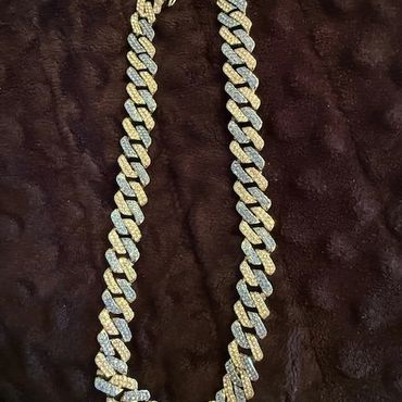 A sparkling diamond-encrusted chain necklace on a dark background.