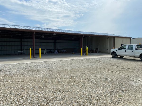 Industrial workshop alongside a white truck in a gravel lot.