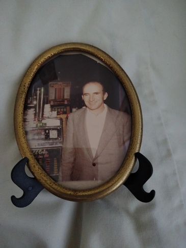Vintage oval photo frame with a black and white portrait of a man in a suit.