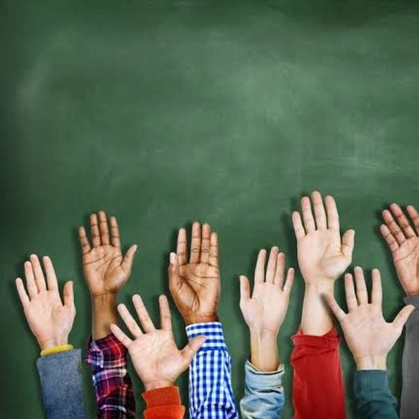 Raised diverse hands against green chalkboard background.