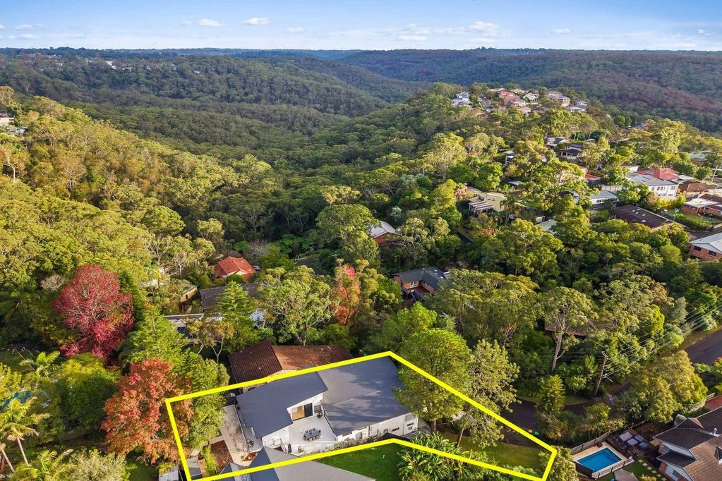 A house surrounded by dense forest with a yellow boundary line.