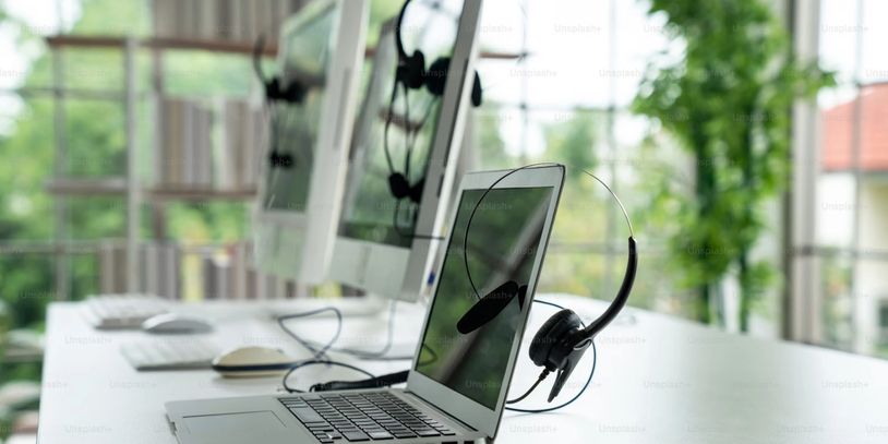 Modern workspace with laptop and headset in a bright office.