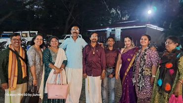 Group of people posing together outdoors at night, dressed in traditional and modern attire.