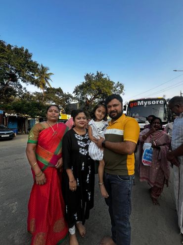Family posing happily on a street with a bus in the background.