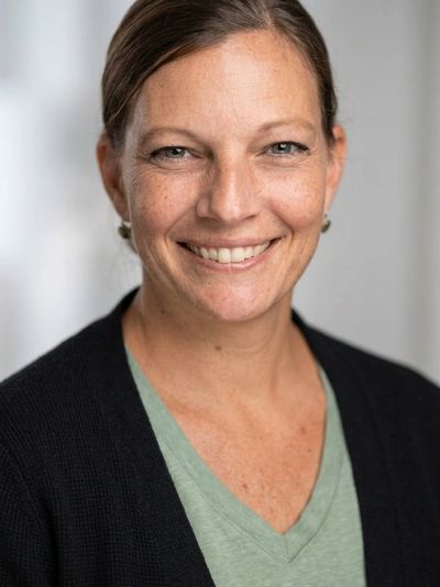 Smiling woman with light brown hair and green shirt.