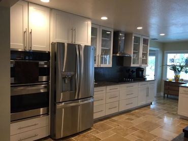 Kitchen remodel with stainless appliances, white shaker cabinets, and stone tile floor.