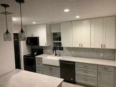 Kitchen remodel with white shaker cabinets, quartz counters, and herringbone backsplash.