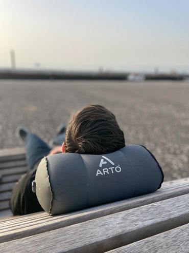 Man using the Arto Pillow - Inflatable while laying on a bench.
