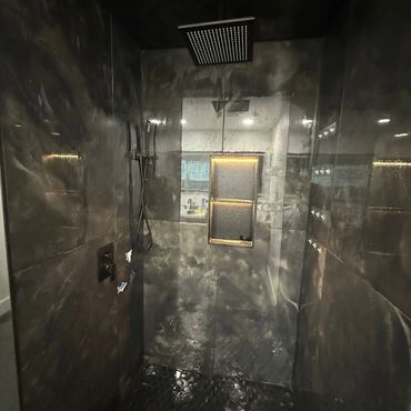 Modern dark-themed shower with rainfall showerhead.