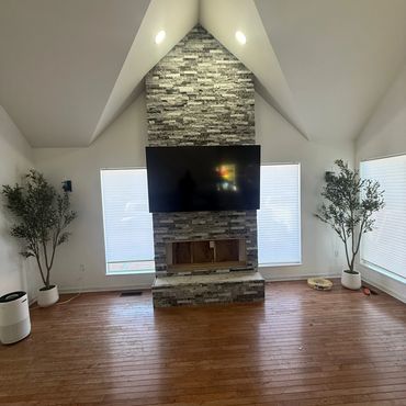 Modern living room with a stone fireplace and TV.