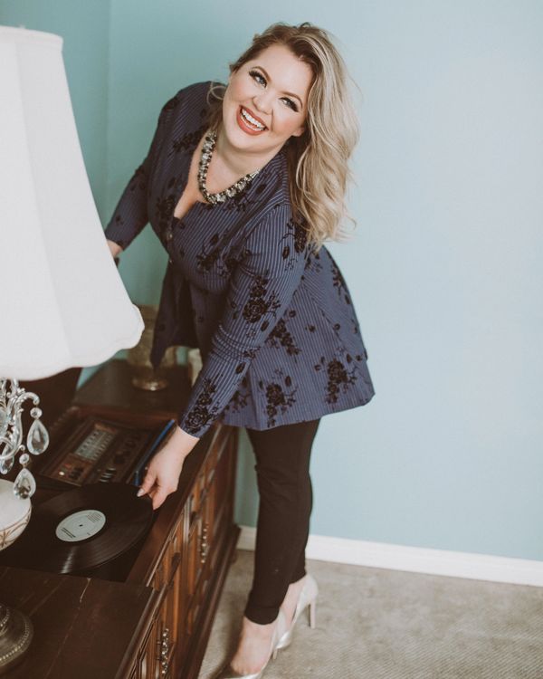 Jayme is putting a record on the turn table and smiling. Blonde hair flipped to the side.