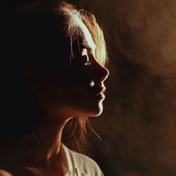 Side profile of a woman illuminated by warm light.