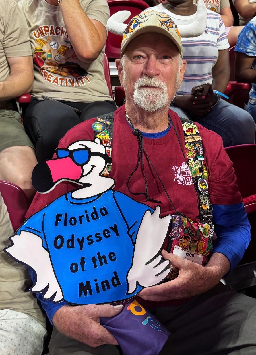 Man holding a sign that says Florida Odyssey of the Mind.