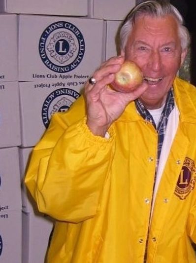 Smiling man in Lions Club jacket with boxes of apples