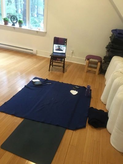 A photograph of a yoga mat and yoga props in a yoga studio, with an open laptop computer reflecting