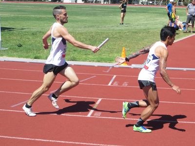 2 Melbourne University Athletics Club members performing a baton change within a relay