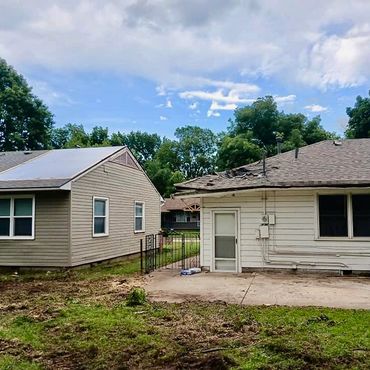 Two houses with a small yard and blue sky.