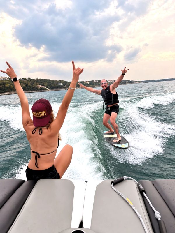 Two people enjoying wakesurfing with triumphant poses.