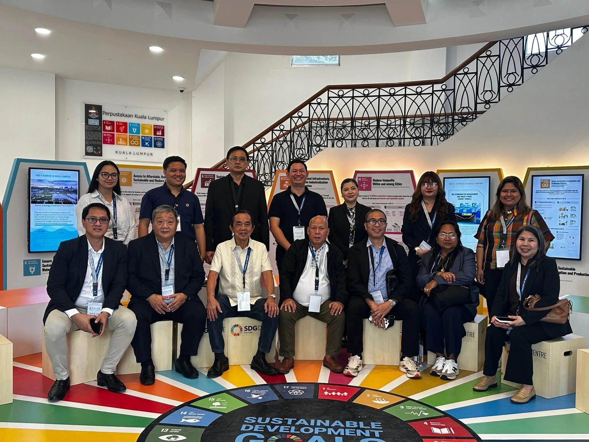 Group photo of professionals in a library with colorful sustainable development graphics.