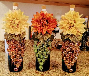 Up-cycled wine bottles using glass gems and silk flowers. Microlights included for ambience.