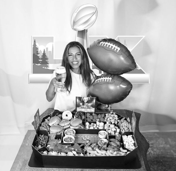 Woman celebrating with football-themed snacks and balloons.