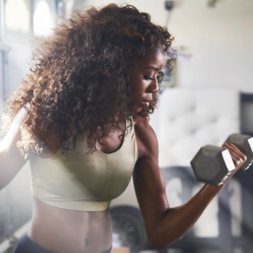 A black woman working out with weights in a fitness gym