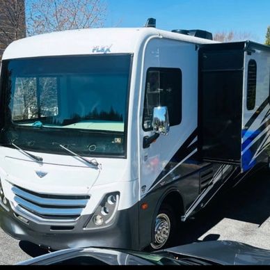 White and black luxury RV parked outdoors with slide-out section extended.