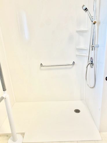 Bathroom renovation with a walk in cultured marble shower base and cultured marble shower panels