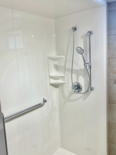 Walk-in cultured marble shower with grab bar and sliding telephone shower head