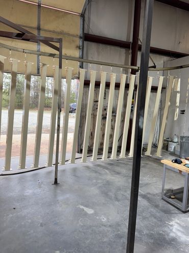 Metal bars hanging for drying or painting in a workshop.