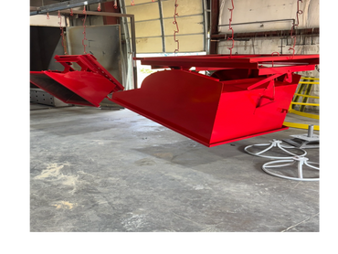 Red metal containers hanging from hooks in an industrial workshop.