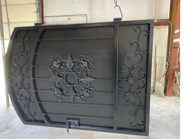 Intricately designed black wrought iron gate with floral and scroll patterns.