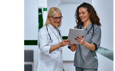 Two female doctors reviewing information on a tablet.