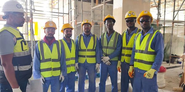 A group of construction workers wearing safety gear at a building site.