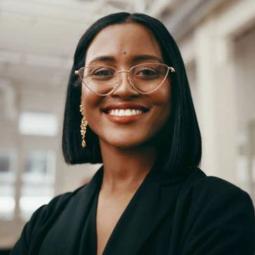 Confident woman with glasses smiling warmly.