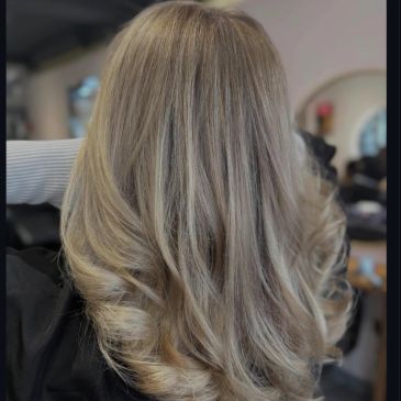 Long layered blonde hair with soft curls.