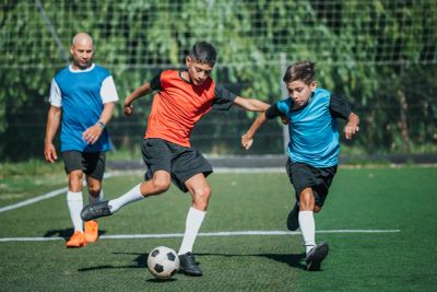 Three males playing soccer on a field.
