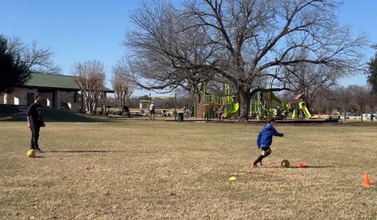 Coach Josh guiding a youth soccer player through a ball-control evaluation at a Cedar Park training