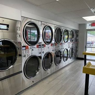 Row of modern stainless steel dryers in a laundromat.