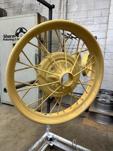 Yellow painted vintage spoked wheel hanging to dry.