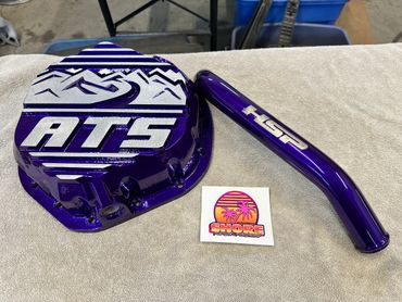 Glossy purple automotive parts with silver logos ATS and HSP on a beige towel.