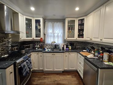 Modern U-shaped kitchen with white cabinets, dark granite countertops, and a tiled backsplash.