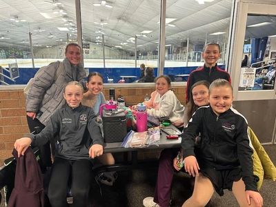 Group of young girls posing indoors near an ice rink.