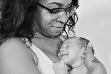 A mother lovingly holding her smiling newborn baby.