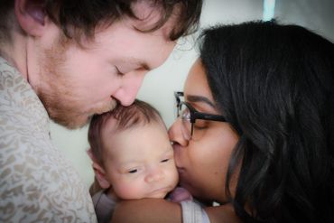 Parents lovingly kiss their baby.