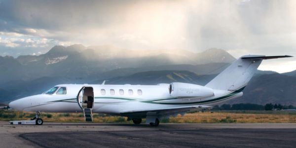 Private jet on a runway with mountains in the background.