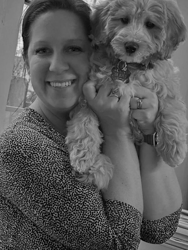 Woman smiling while holding a fluffy dog named Oliver.
