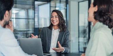 Businesswoman smiling and discussing with colleagues in a modern office.